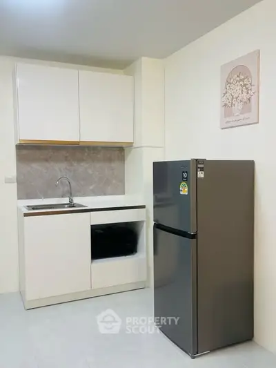 Modern kitchen with sleek cabinetry and stainless steel fridge in a compact layout.
