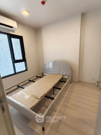 Spacious bedroom with natural light and modern design, featuring a new bed frame and air conditioning.