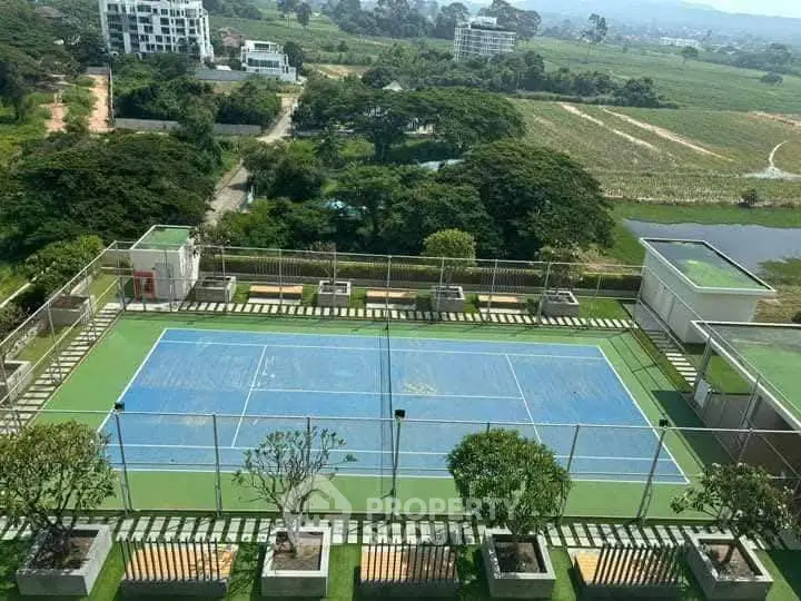 Stunning aerial view of a tennis court surrounded by lush greenery in a modern residential complex.
