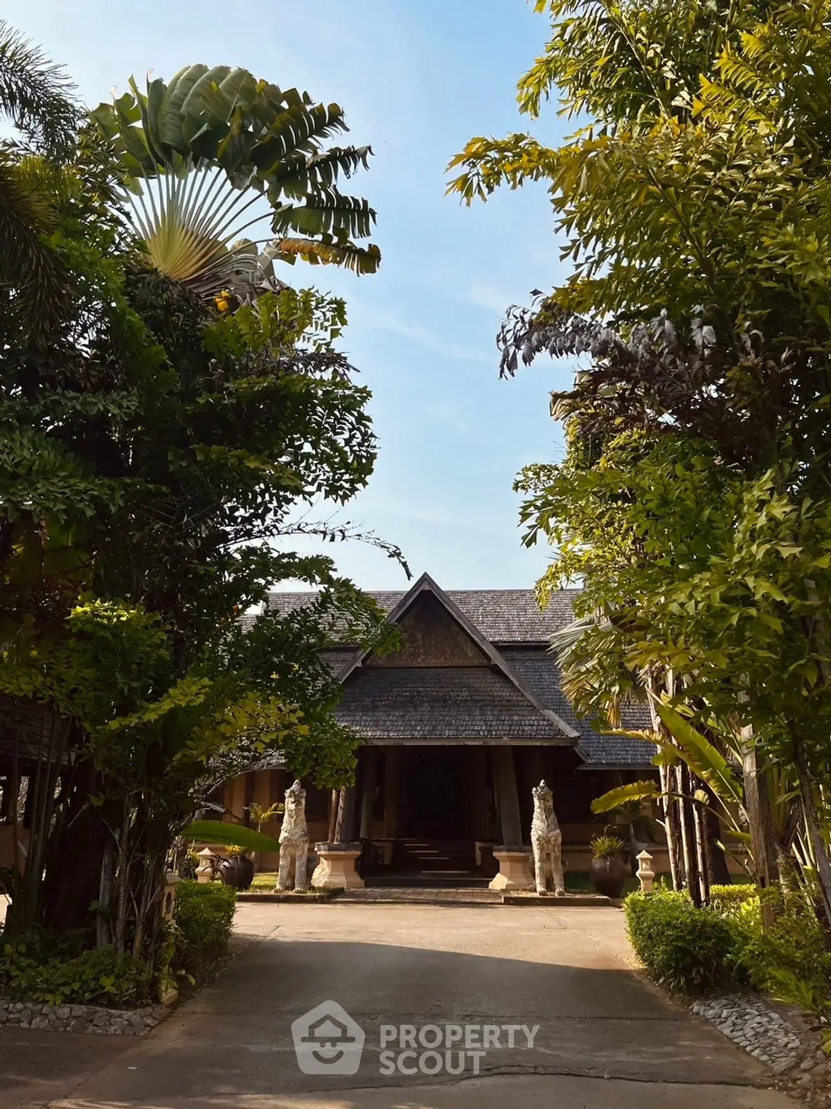 Stunning tropical villa entrance surrounded by lush greenery and elegant statues.