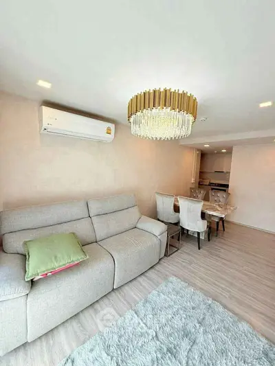 Elegant living room with plush sofa, chic chandelier, and dining area in modern apartment.