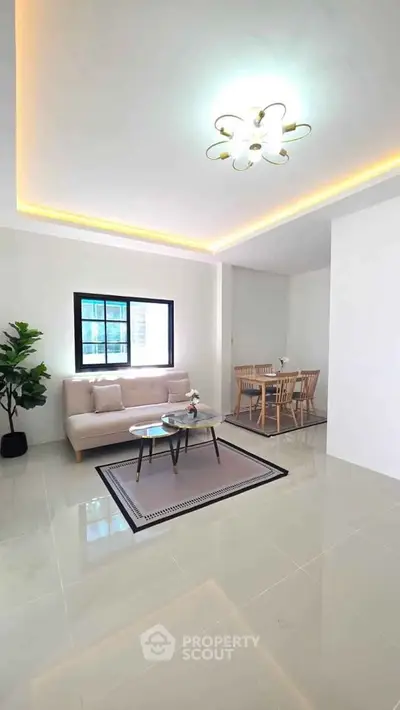 Modern living room with elegant lighting and dining area, featuring sleek furniture and a cozy atmosphere.