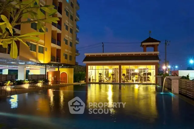 Luxurious apartment complex with illuminated pool and modern gym at dusk.