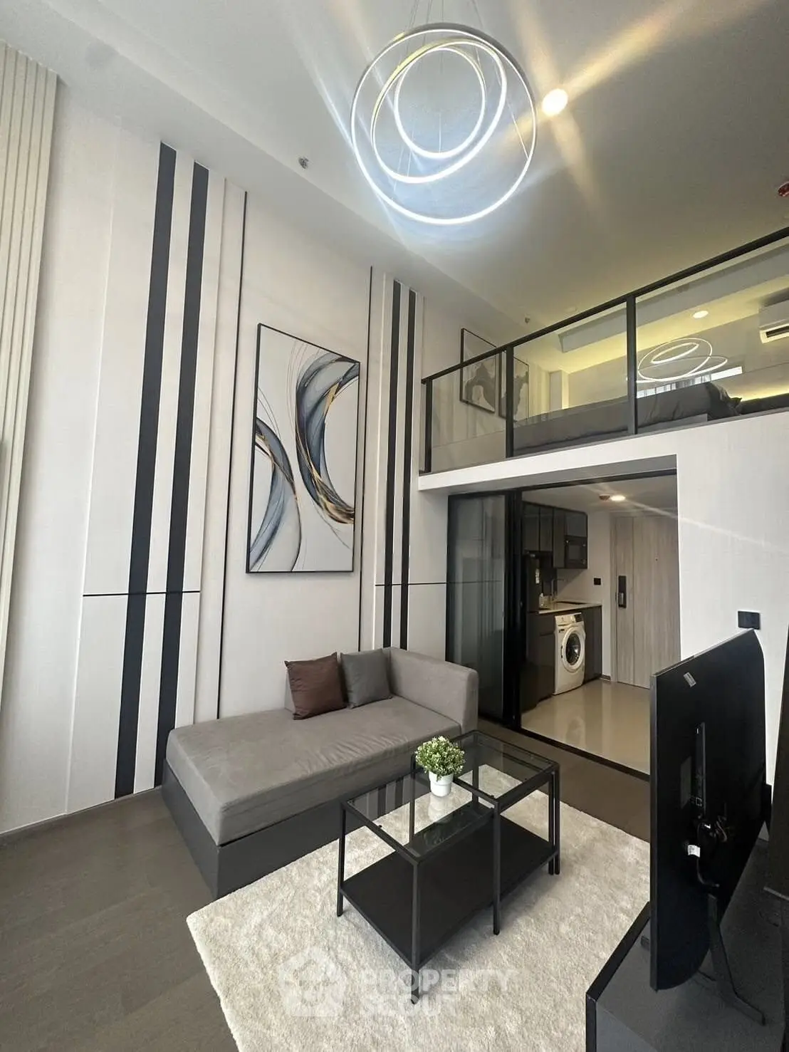 Modern loft apartment with stylish living room and mezzanine bedroom, featuring sleek furniture and contemporary lighting.