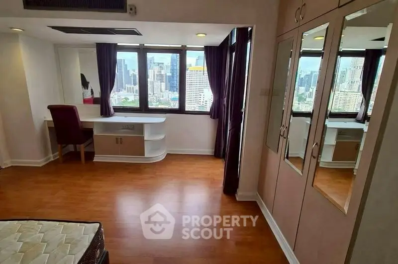Spacious bedroom with city view, hardwood floors, and built-in wardrobe in modern apartment.