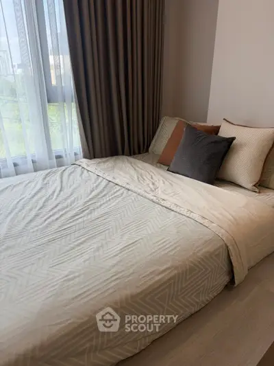 Cozy bedroom with elegant bedding and large window offering natural light
