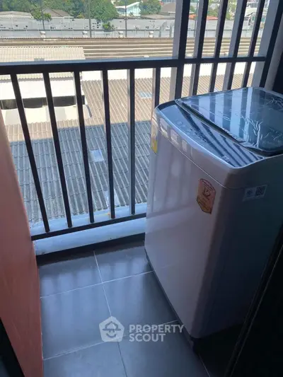 Compact balcony with washing machine and city view, ideal for urban living.