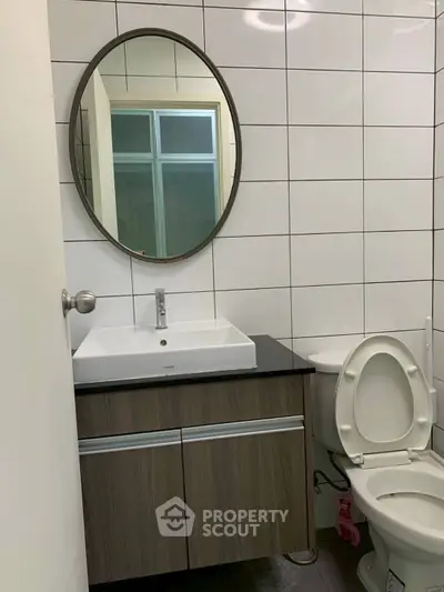 Modern bathroom with sleek vanity and round mirror in a contemporary home.