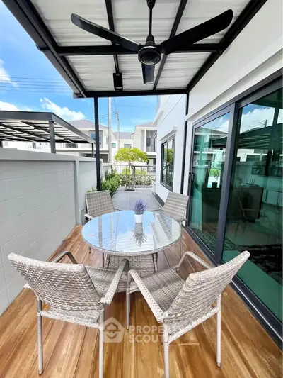 Charming balcony with modern outdoor furniture and ceiling fan, perfect for relaxation.