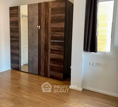 Spacious bedroom with modern wardrobe and wooden flooring, perfect for stylish living.