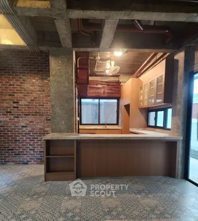Industrial-style kitchen with exposed brick and concrete, featuring open layout and modern cabinetry.