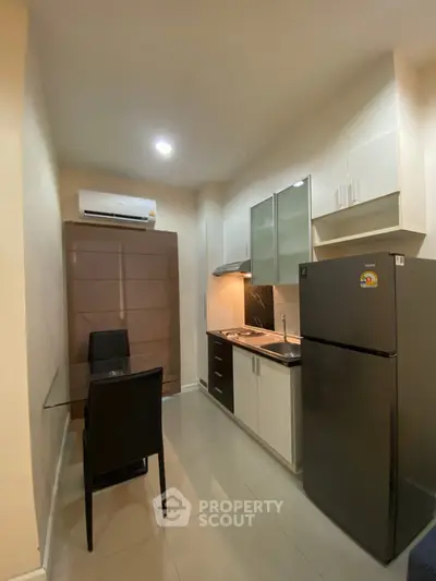 Modern compact kitchen with dining area, featuring sleek appliances and stylish cabinetry.
