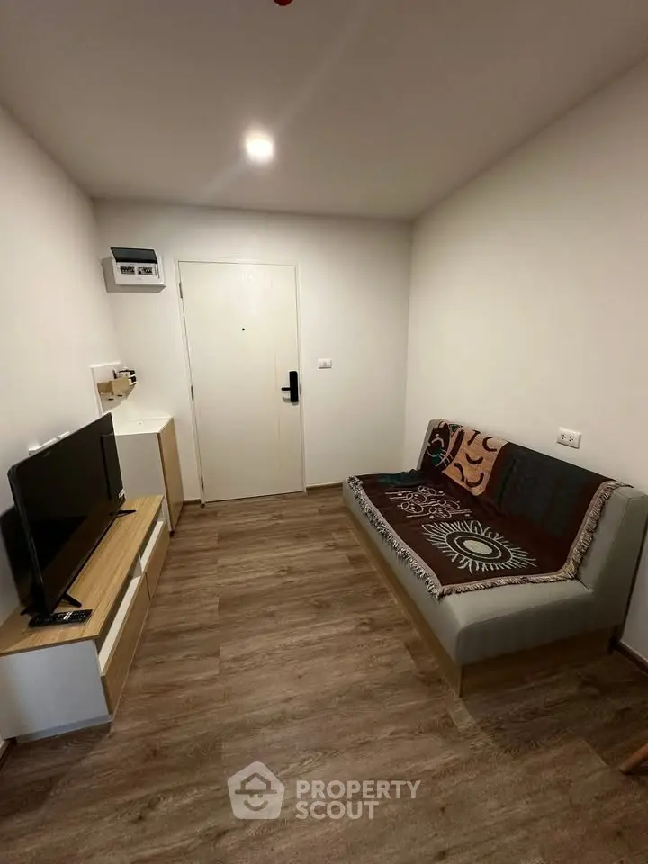Cozy living room with modern decor and wooden flooring, featuring a stylish sofa and entertainment unit.