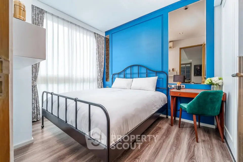 Stylish bedroom with modern decor and vibrant blue accent wall, featuring a cozy bed and elegant furnishings.