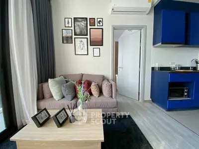Modern living room with stylish decor and compact kitchen in a cozy apartment setting.