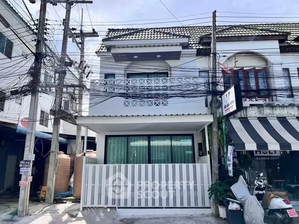 Charming two-story townhouse with modern facade and balcony in urban setting.