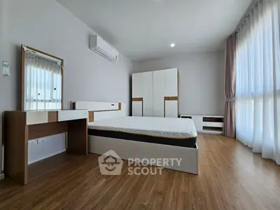 Spacious modern bedroom with wooden flooring and ample natural light