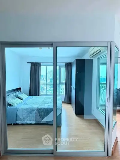Spacious bedroom with city view and modern decor in high-rise apartment.
