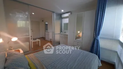 Spacious bedroom with modern decor and ample natural light, featuring a large wardrobe and stylish furnishings.