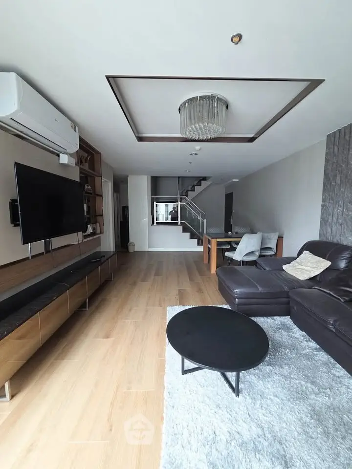Spacious modern living room with elegant decor and open layout, featuring a stylish chandelier and sleek furniture.