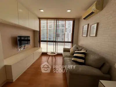 Cozy living room with modern decor, featuring a comfortable sofa, wall-mounted TV, and large windows for natural light.