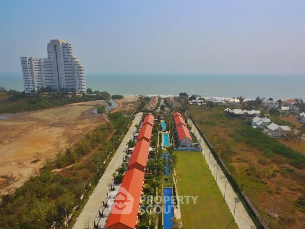 Stunning aerial view of beachfront property with modern high-rise and charming villas.