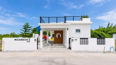Modern white house exterior with sleek design and rooftop terrace in a serene neighborhood.