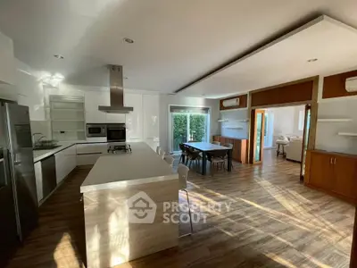 Spacious modern kitchen with open layout and dining area, featuring sleek appliances and wooden flooring.