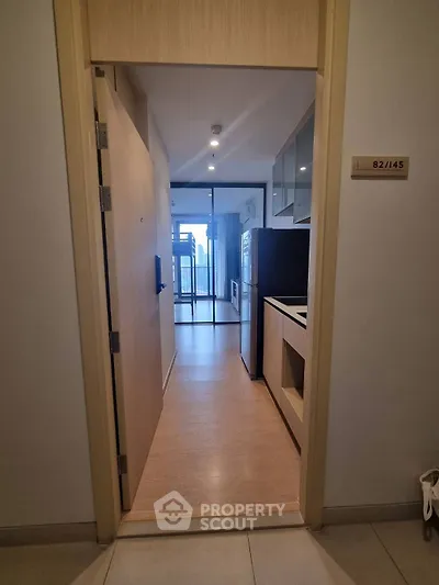 Modern apartment entrance with sleek kitchen and open living area, featuring floor-to-ceiling windows.