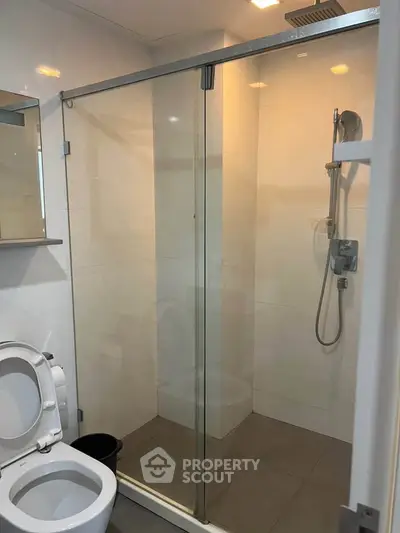 Modern bathroom with glass shower enclosure and sleek fixtures in a contemporary apartment.