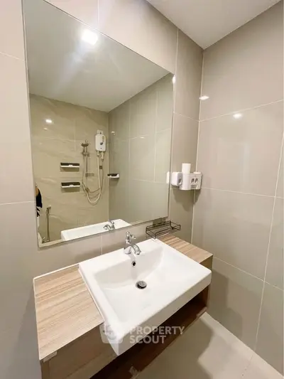 Modern bathroom with sleek sink and large mirror in stylish apartment.