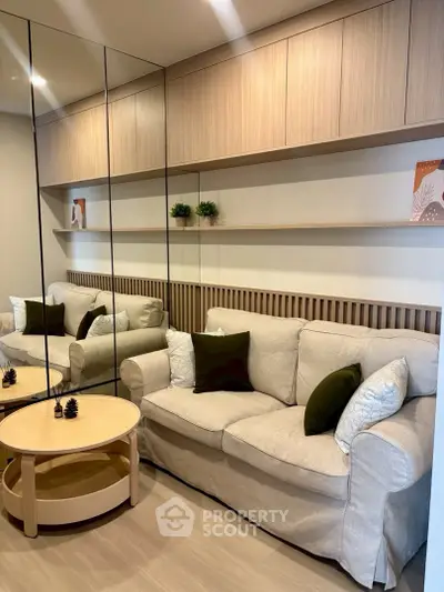 Modern living room with cozy beige sofa, mirrored wall, and stylish wooden shelves.