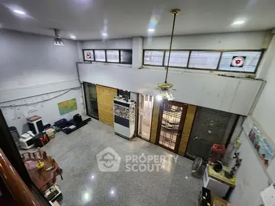 Spacious industrial-style room with high ceilings and large windows, ideal for creative workspace or studio.