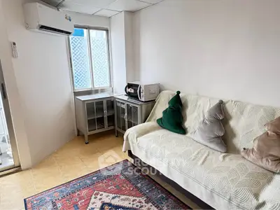 Cozy living room with air conditioning and modern decor, featuring a comfortable sofa and a stylish rug.