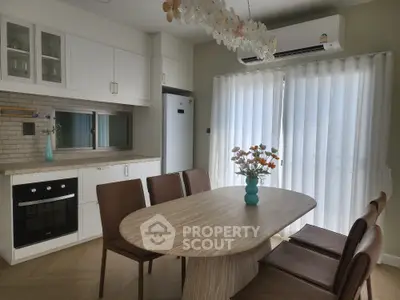 Modern kitchen with dining area featuring elegant table and chairs, stylish cabinetry, and natural light.