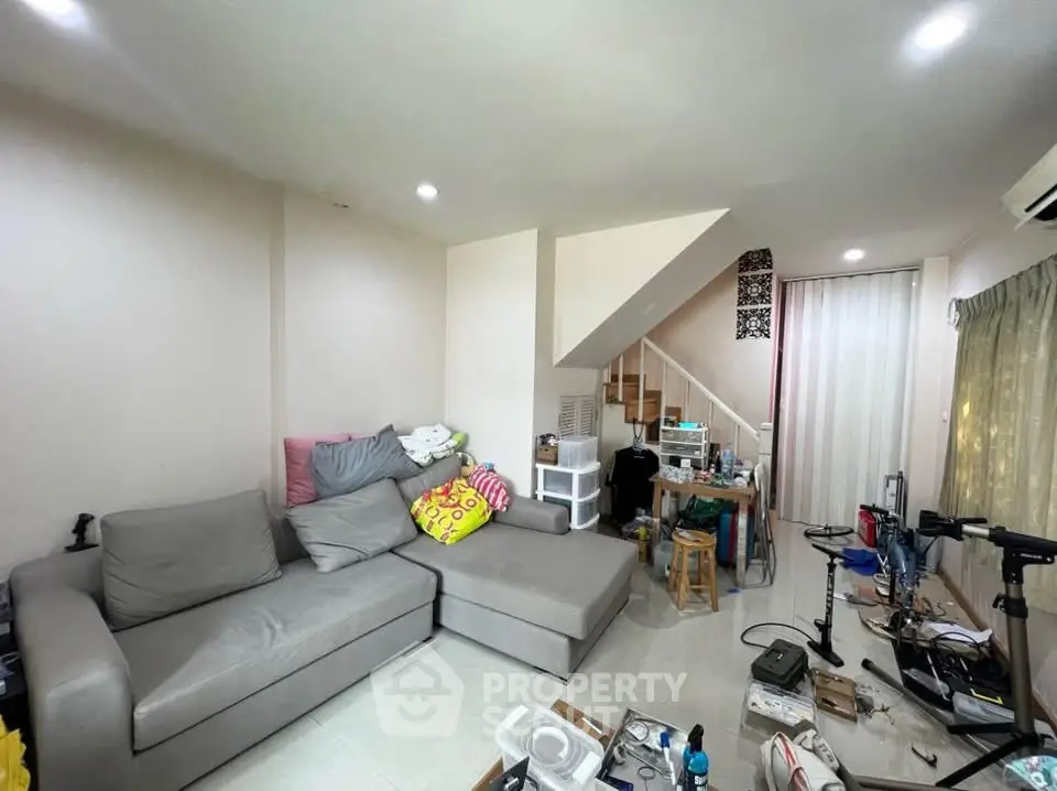Cozy living room with modern gray sofa and staircase, ideal for family gatherings.