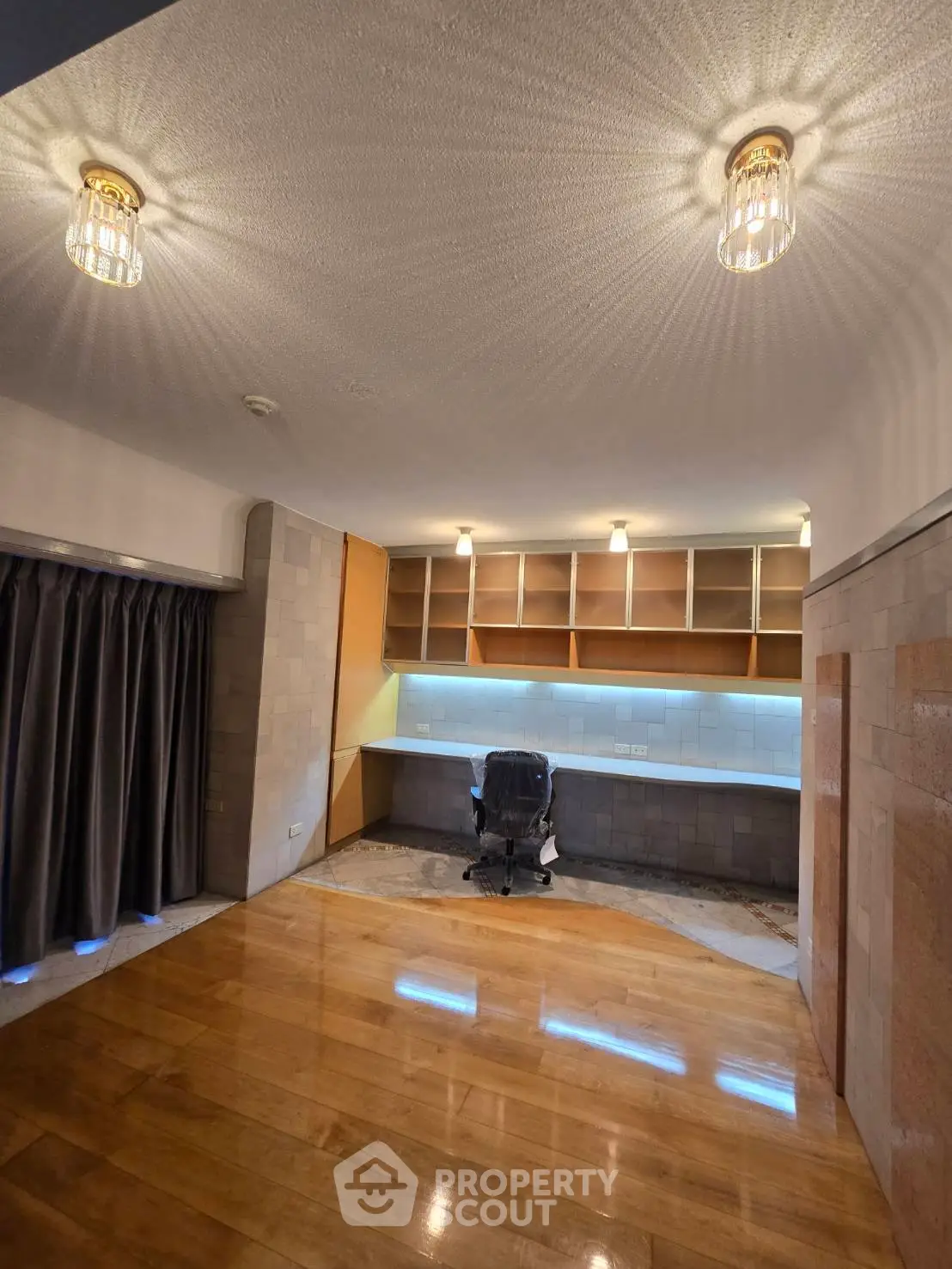 Spacious study room with modern lighting and built-in shelves, perfect for productivity and comfort.