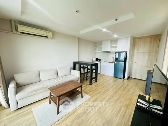 Modern living room with open kitchen, featuring sleek furniture and natural light.