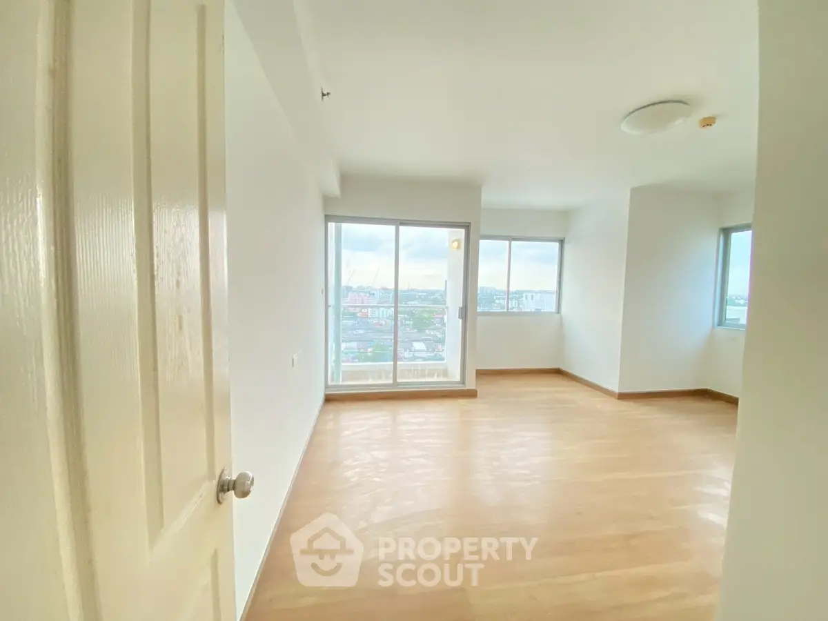 Spacious empty room with large windows offering panoramic city views.