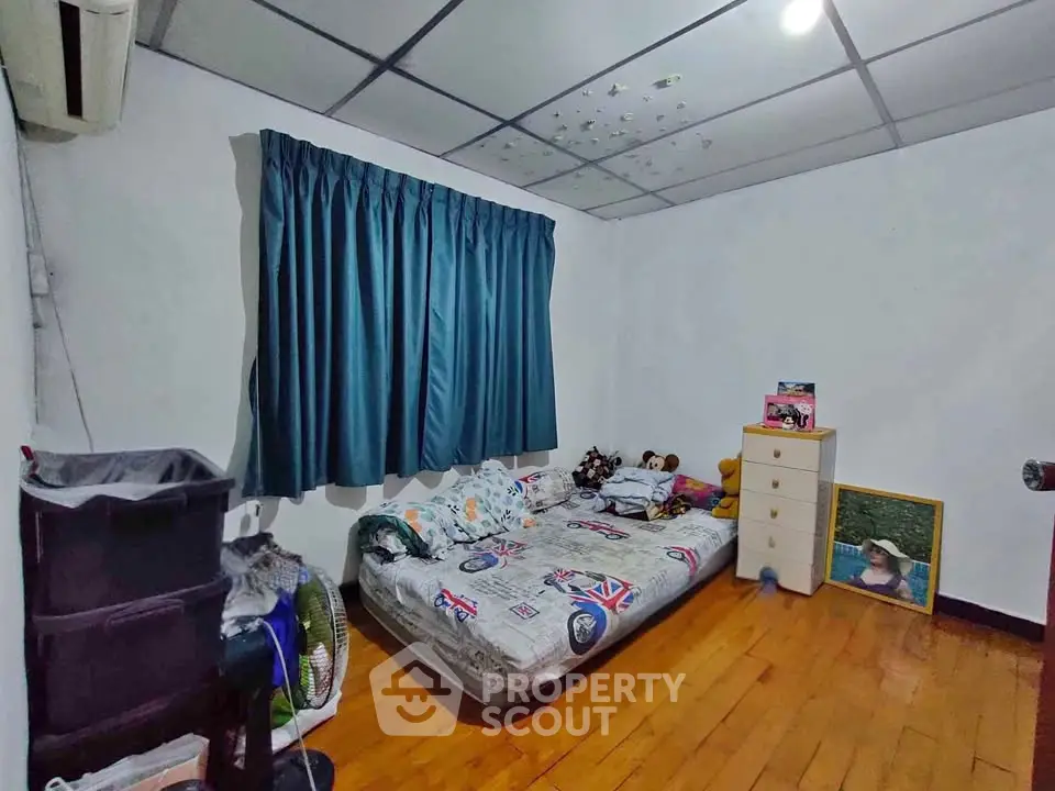 Cozy bedroom with wooden flooring and blue curtains, featuring a comfortable bed and ample storage space.