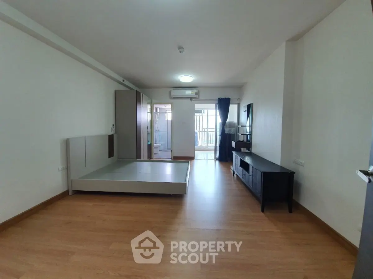 Spacious unfurnished bedroom with wooden flooring and balcony access.