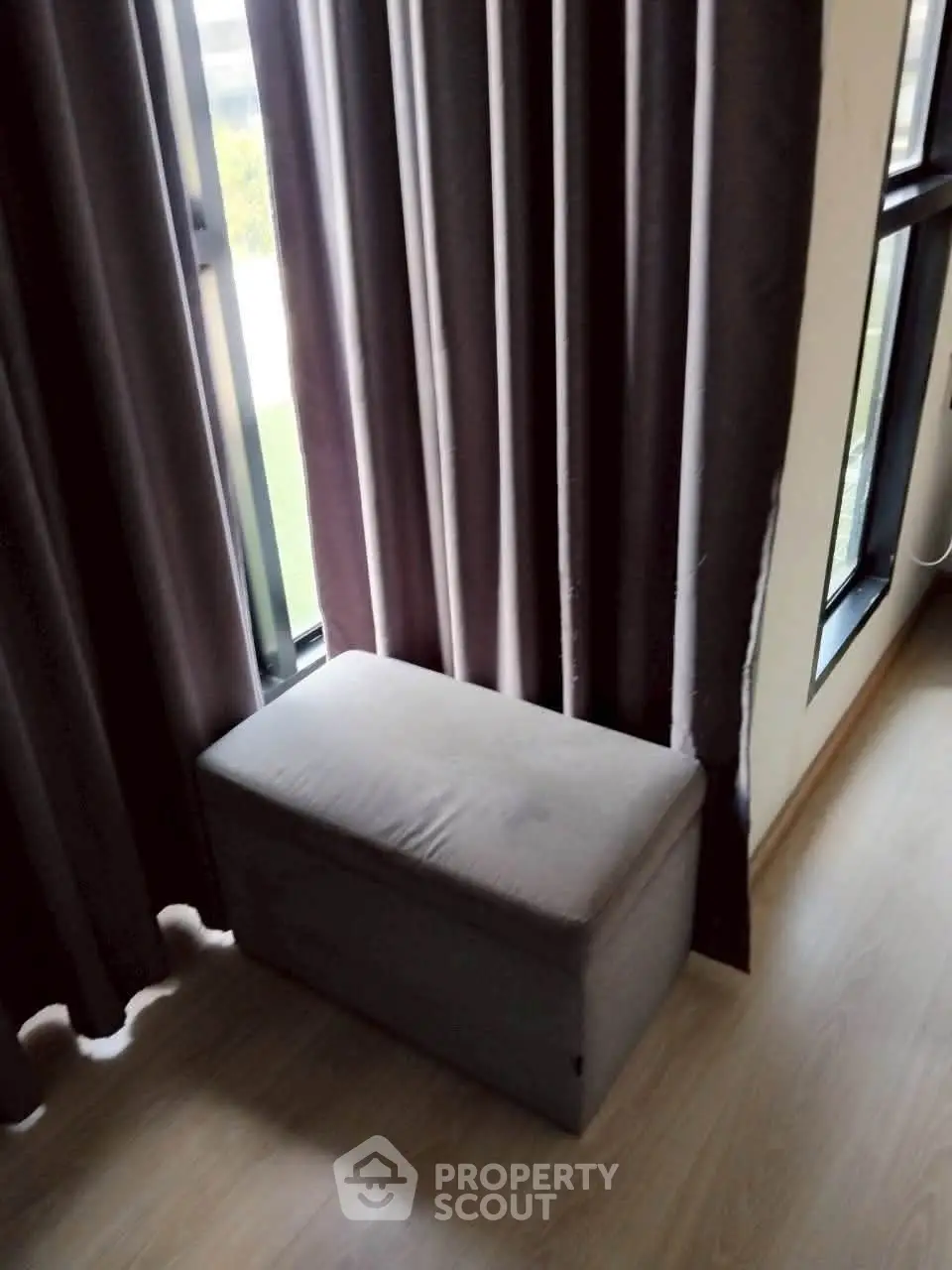 Cozy corner with elegant curtains and a stylish ottoman in a modern apartment.