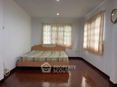 Spacious bedroom with wooden flooring and large windows for natural light.