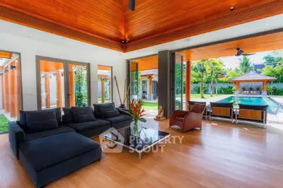 Luxurious living room with pool view, featuring modern furniture and expansive glass doors opening to a tropical garden.