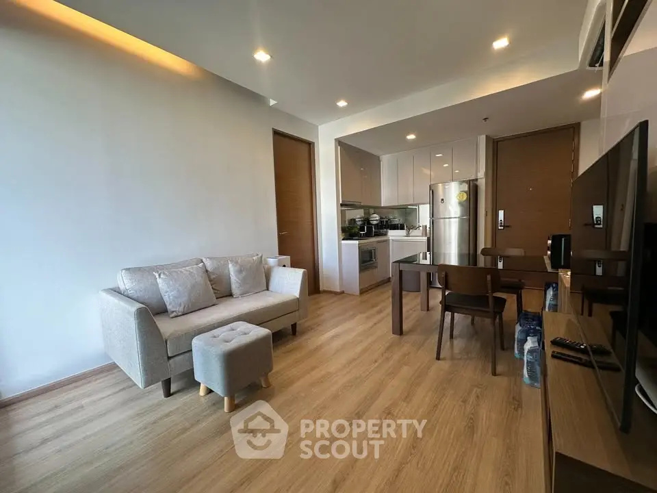 Modern living room with open kitchen, sleek furniture, and wooden flooring in a stylish apartment.