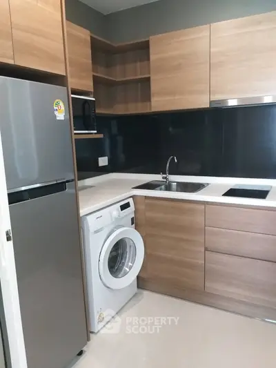 Modern kitchen with wooden cabinets, washing machine, and sleek appliances.