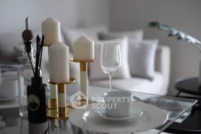 Elegant dining setup with candles and glassware in a modern living room setting.