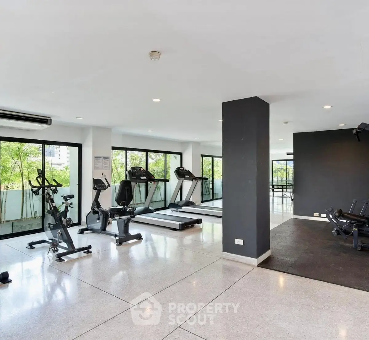 Spacious modern gym with large windows and fitness equipment in a residential building.
