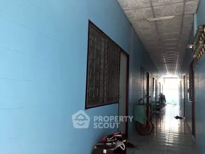 Long corridor in residential building with blue walls and tiled floor.
