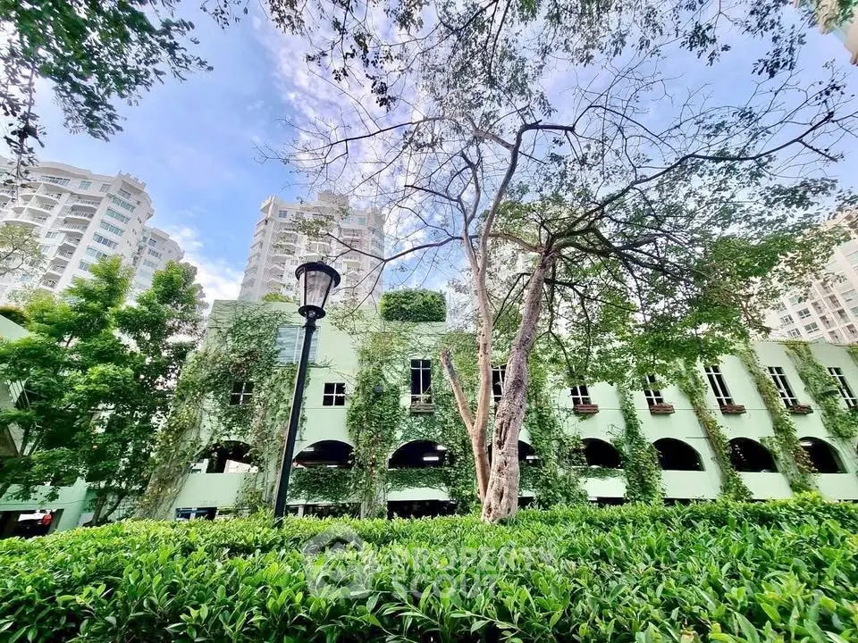 Stunning green building facade with lush foliage and modern high-rise backdrop.